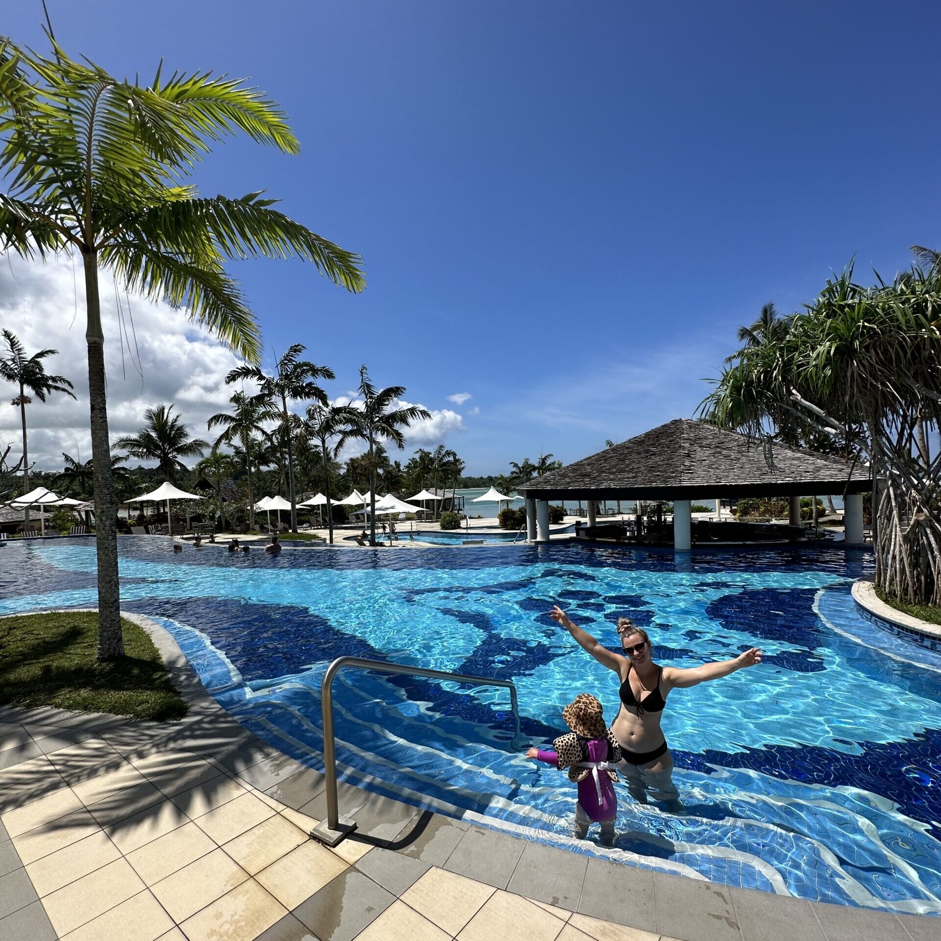 Tonia, Jayden, and Hailey relaxing by the pool at Warwick Le Lagon during their family holiday in Vanuatu.
