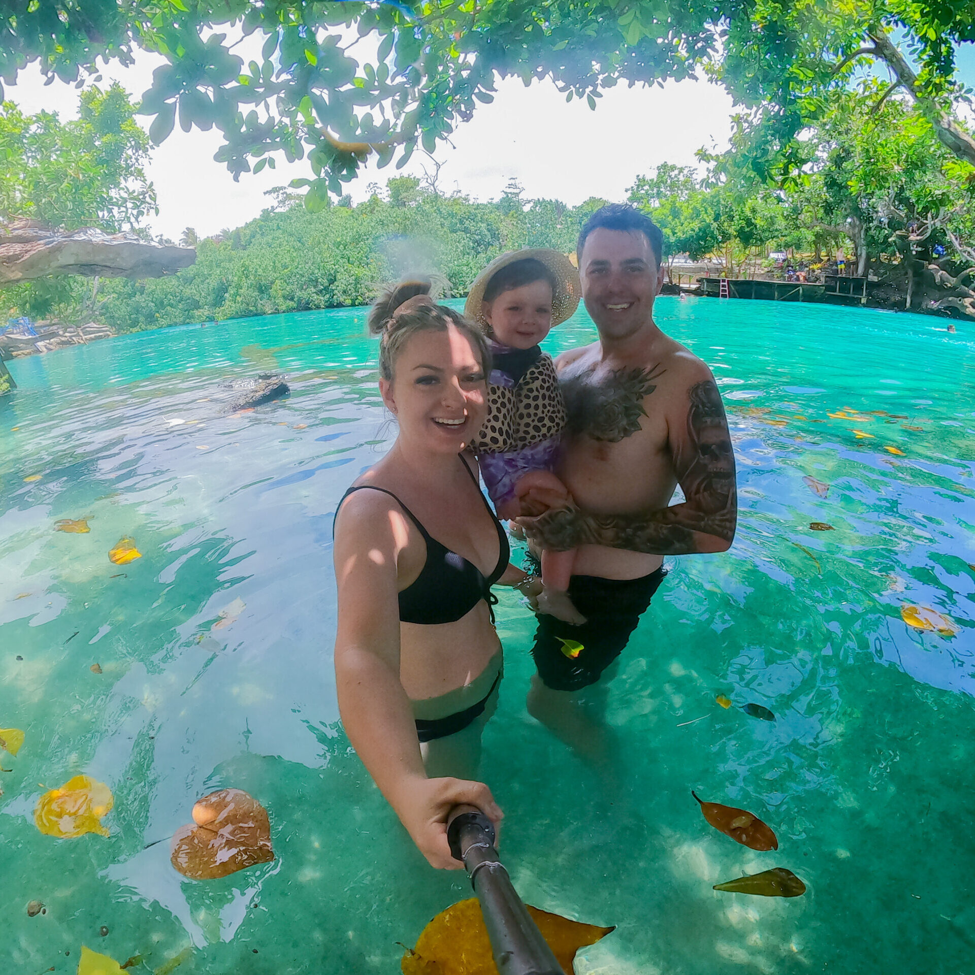 Three family members enjoying the crystal-clear waters of the Blue Lagoon in Vanuatu, sharing smiles and moments while discussing entry requirements: things you need to know