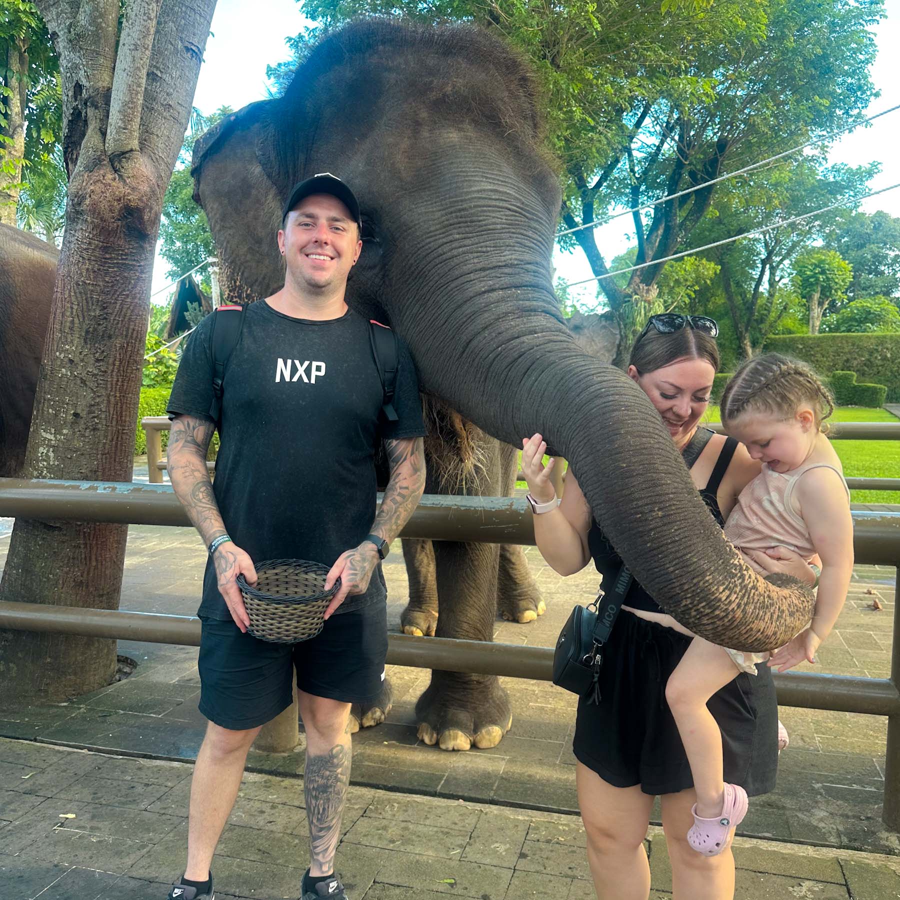 Family visiting an elephant sanctuary in Bali, sharing a close moment with an elephant while travelling together.